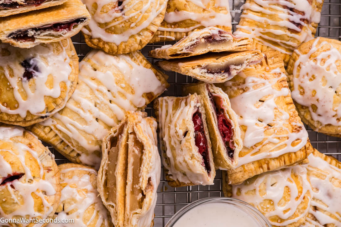 These easy hand pies are a master recipe for any filling — from Black Forest cherry to caramel apple! Flaky, simple, and ready in minutes. #handpies #easypies easy hand pies drizzled with glaze on a serving platter