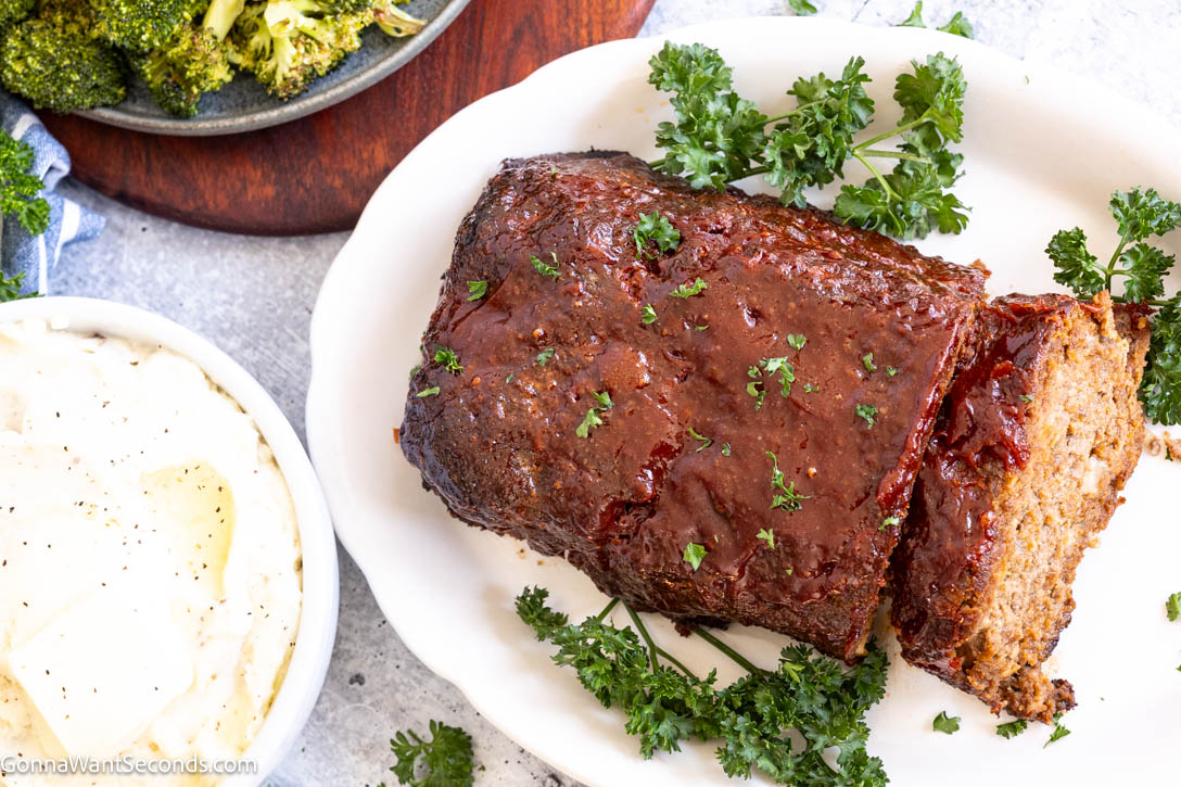 This Lipton Onion Soup Meatloaf is juicy, flavorful, and topped with a tangy glaze—classic comfort food made easy and always perfectly tender. #meatloaf #liptononionsoup whole Lipton Onion Soup Meatloaf with a slice taken out, showing the juiciness inside