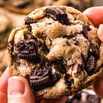 hand holding a piece of Oreo chocolate chip cookies