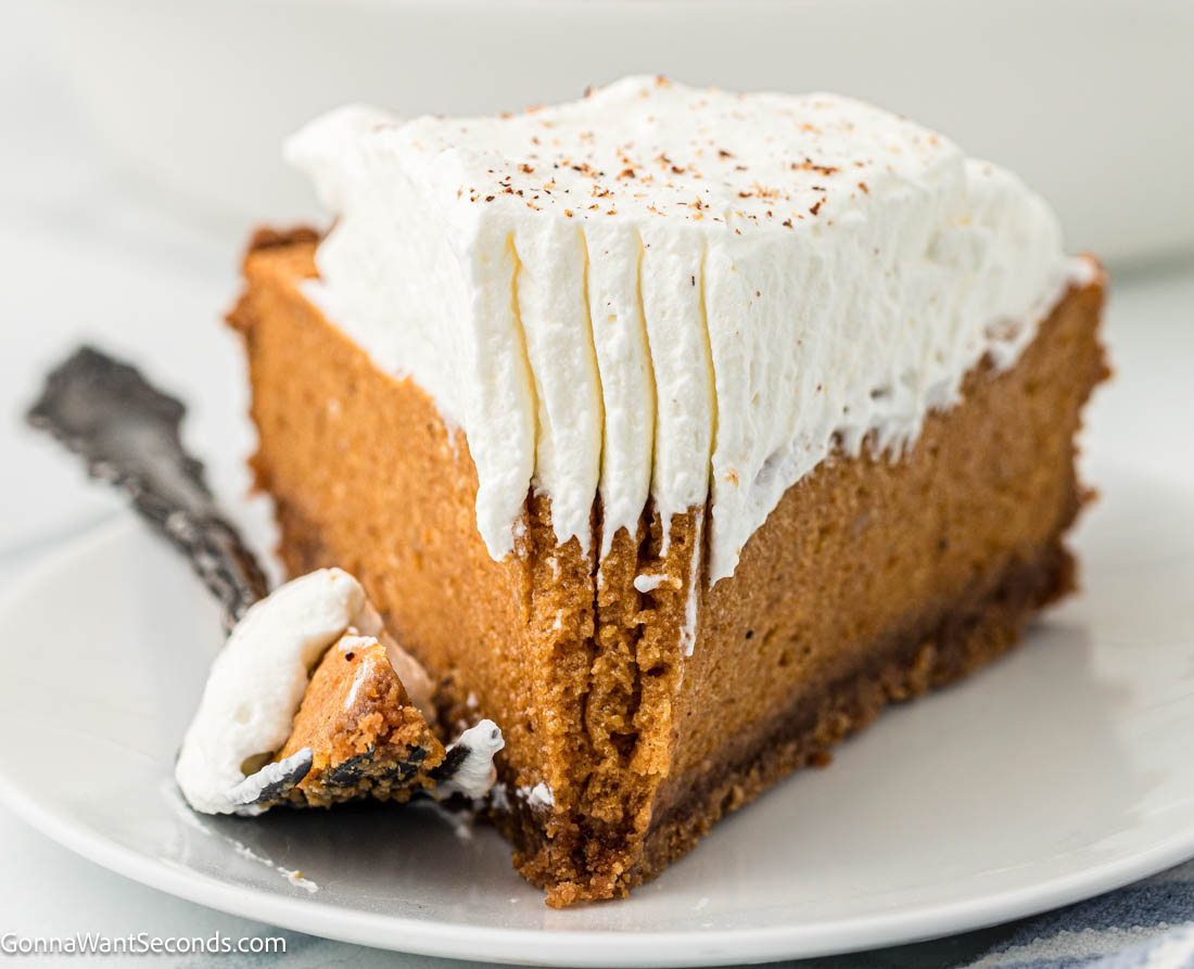 Light, airy pumpkin chiffon pie with warm spices and a buttery Biscoff crust. A dreamy make-ahead holiday dessert your family will love. #pumpkinpie #chiffonpie a slice of pumpkin chiffon pie on a plate