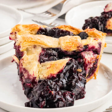 a slice of Razzleberry Pie with the filling spilling out on a plate