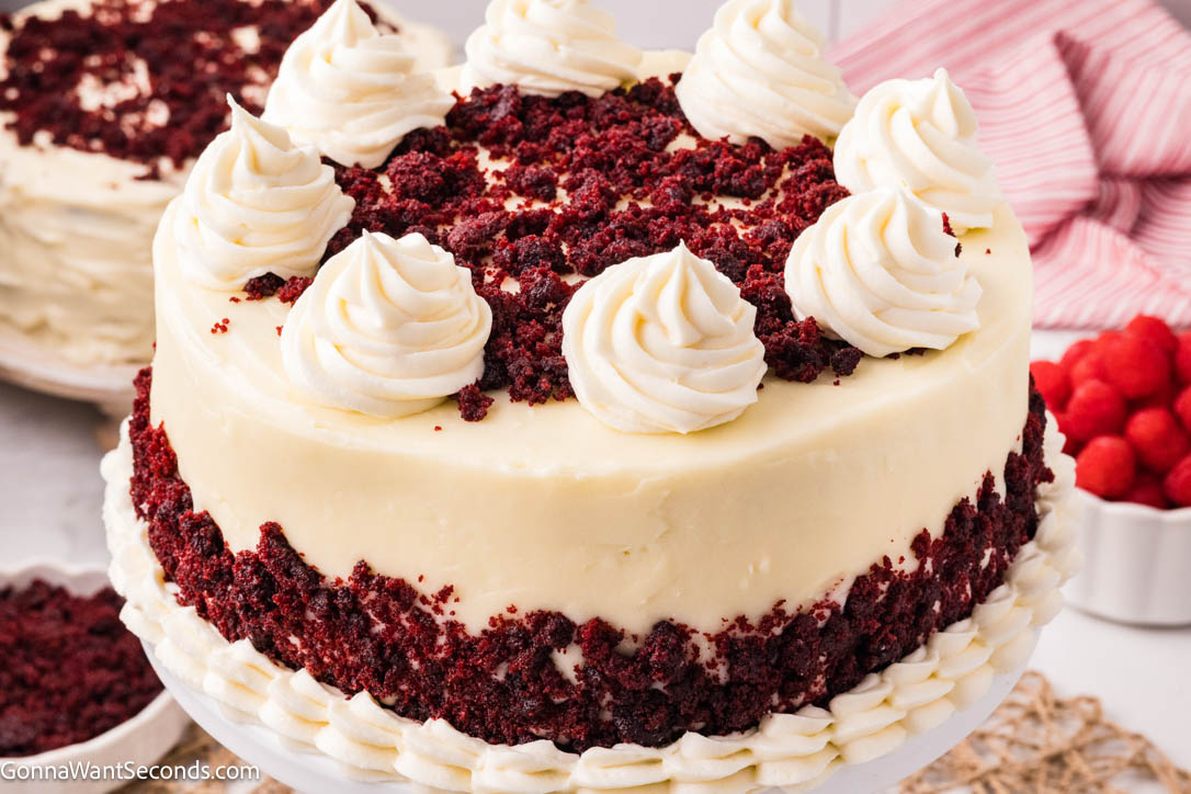 Red velvet cake is ultra moist, cocoa-kissed, and topped with tangy cream cheese frosting—an easy, bakery-style classic your family will crave. #redvelvetcake #redvelvet Red velvet cake topped with cream cheese frosting with decor