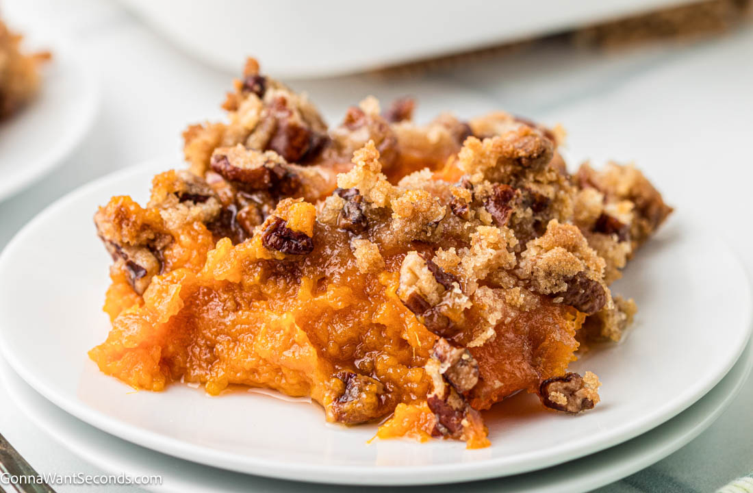 This Ruth’s Chris Sweet Potato Casserole has silky smooth sweet potatoes, with golden and crisp brown sugar–pecan topping. It's the best holiday side dish! #sweetpotatoes #sweetpotatocasserole A serving of Ruth’s Chris Sweet Potato Casserole with golden and crisp brown sugar–pecan topping on a plate