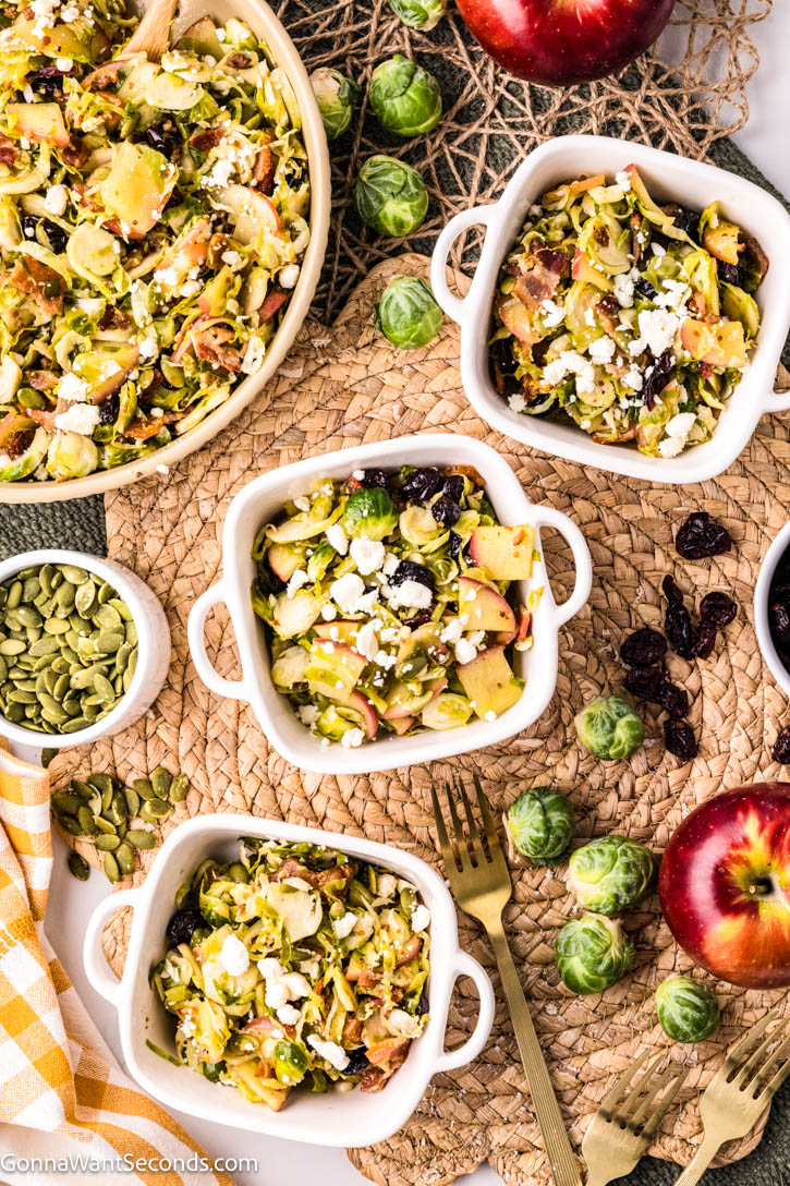 Warm shaved Brussels sprouts salad with apples, bacon, cranberries, and feta in a maple mustard dressing — cozy, colorful, and ready in 20 minutes! #Brusselssprout #Brusselssproutsalad bowls of shaved Brussels sprouts salad with apples, bacon, cranberries, and feta
