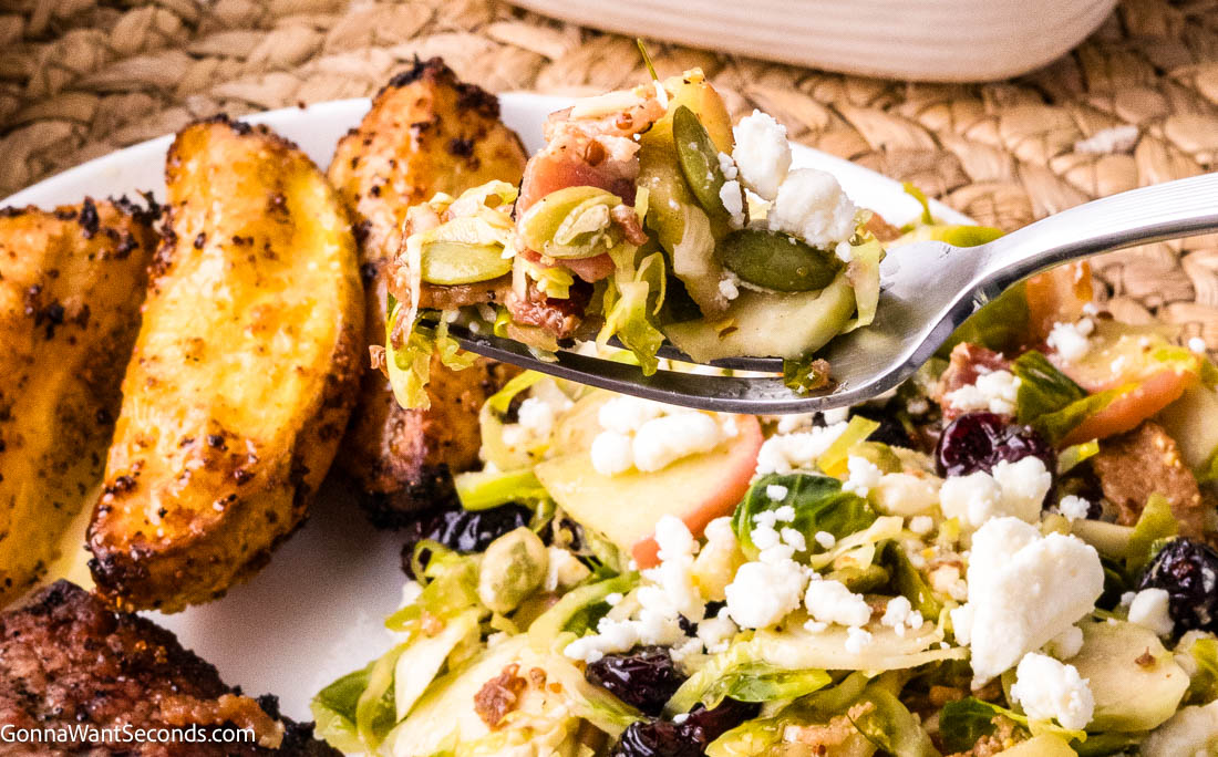 a forkful of shaved Brussels sprouts salad with apples, bacon, cranberries