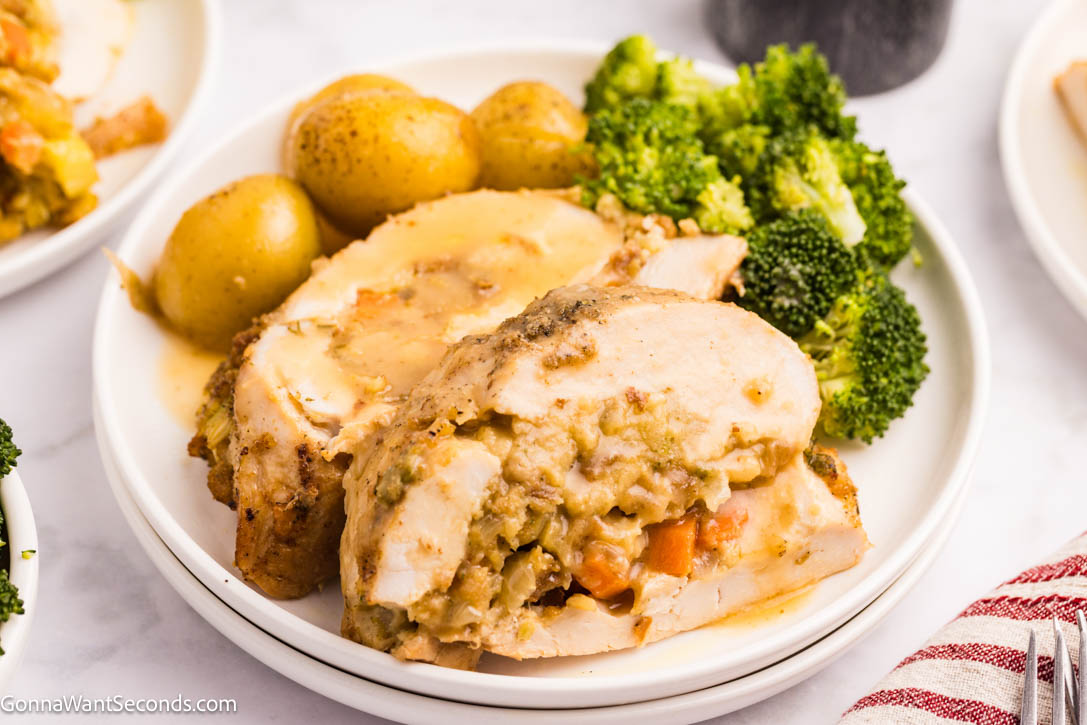 This Stuffed Turkey Breast is tender, juicy, and filled with a cozy apple-herb stuffing that tastes like the very best parts of Thanksgiving. #stuffedturkeybreast #turkeybreast Stuffed Turkey Breast with apple-herb stuffing on a plate with gravy on top