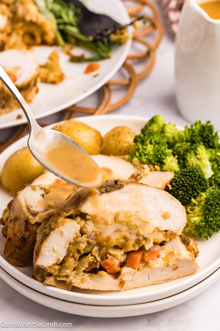This Stuffed Turkey Breast is tender, juicy, and filled with a cozy apple-herb stuffing that tastes like the very best parts of Thanksgiving. #stuffedturkeybreast #turkeybreast Gravy pouring over Stuffed Turkey Breast with apple-herb stuffing