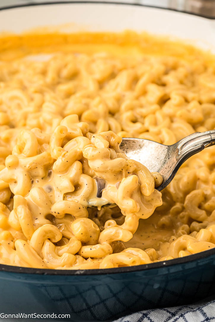 Ultra-creamy Velveeta Mac and Cheese made with milk, mustard, + a dash of Tabasco for brightness — a cozy, nostalgic classic everyone loves. #velveetamacandcheese #macandcheese serving spoon scooping velveeta mac and cheese