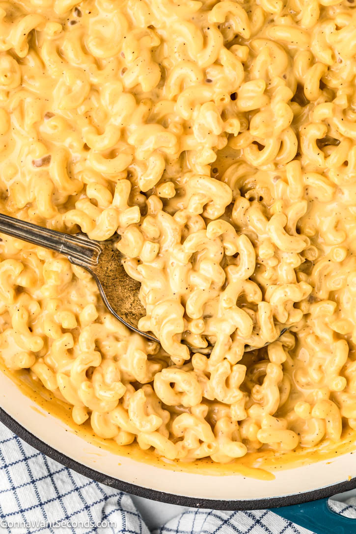 Ultra-creamy Velveeta Mac and Cheese made with milk, mustard, + a dash of Tabasco for brightness — a cozy, nostalgic classic everyone loves. #velveetamacandcheese #macandcheese serving spoon scooping velveeta mac and cheese