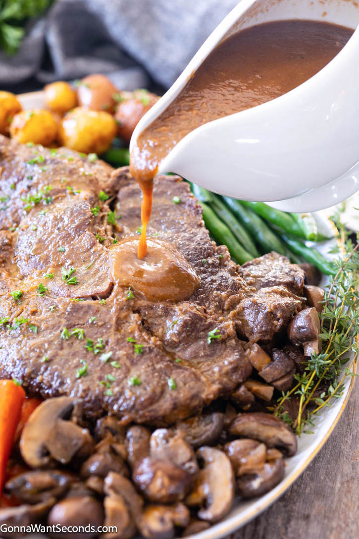 Mouthwateringly, melt-in-your-mouth braised chuck roast with silky blended gravy made right from the braising liquid—no extra thickeners needed!! #braisedbeef #braisedchuckroast pouring gravy over braised chuck roast