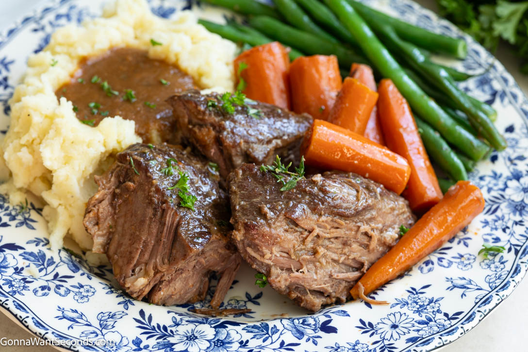 Mouthwateringly, melt-in-your-mouth braised chuck roast with silky blended gravy made right from the braising liquid—no extra thickeners needed!! #braisedbeef #braisedchuckroast braised chuck roast with veggies and mashed potatoes on a plate