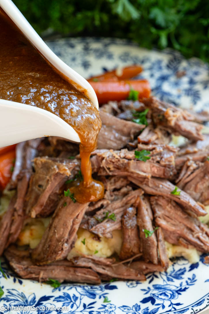 Mouthwateringly, melt-in-your-mouth braised chuck roast with silky blended gravy made right from the braising liquid—no extra thickeners needed!! #braisedbeef #braisedchuckroast pouring gravy over braised chuck roast