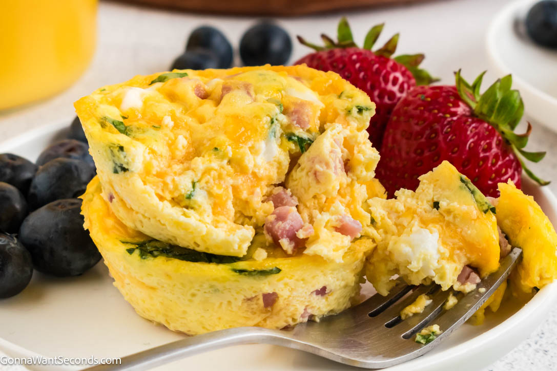 These easy breakfast egg muffins are fluffy, customizable, and perfect for meal prep. Make ahead, freeze, and reheat for busy mornings. #breakfastmuffins #eggmuffins breakfast egg muffins with ham, with fruits on the side