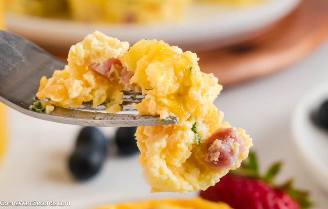 These easy breakfast egg muffins are fluffy, customizable, and perfect for meal prep. Make ahead, freeze, and reheat for busy mornings. #breakfastmuffins #eggmuffins a fork piercing a piece of breakfast egg muffins with ham