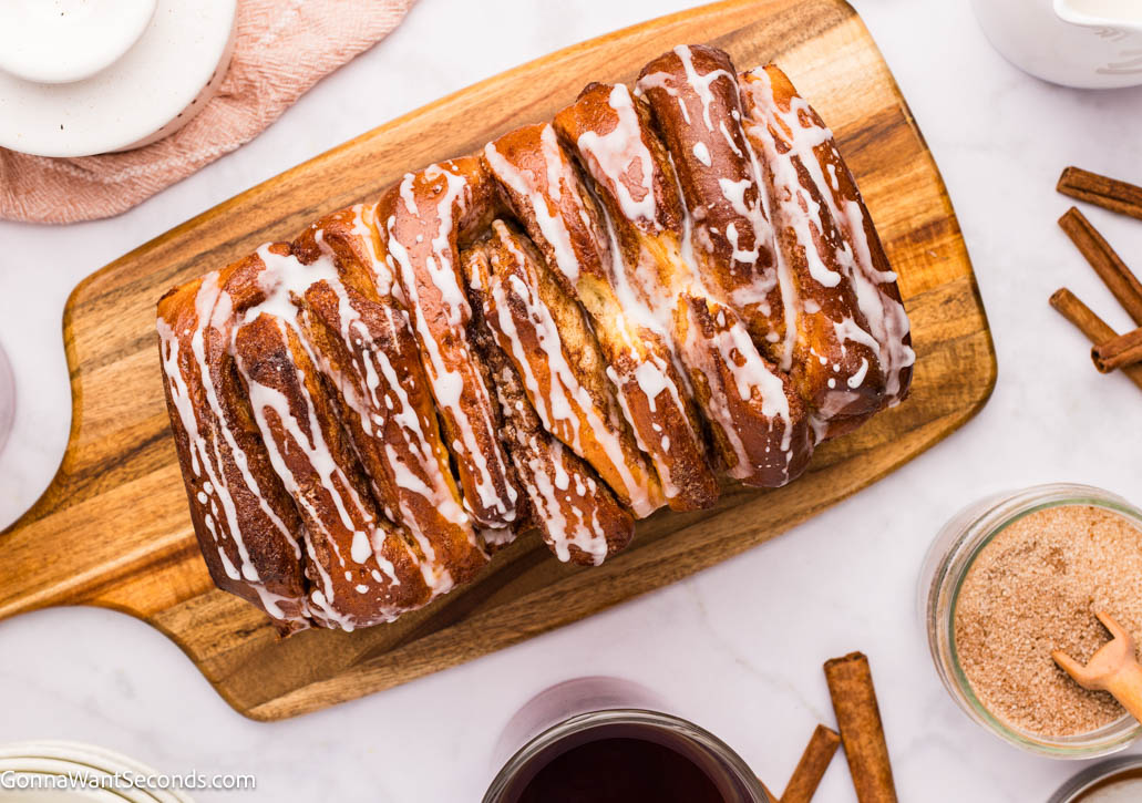Soft, gooey cinnamon pull apart bread with buttery layers and a sweet powdered sugar glaze—perfect for brunches and holidays in a 9x5 loaf today! #cinnamonbread #pullapartbread cinnamon pull apart bread with sweet powdered sugar glaze dripping, top shot