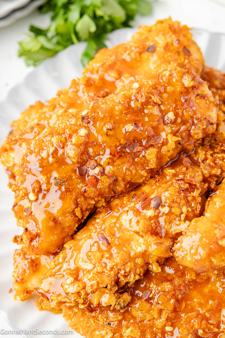 These Hot Honey Chicken Tenders are baked in the oven with a crunchy cornflake coating and finished with a sticky-sweet, lightly spicy hot honey glaze. #chickentenders #hothoneychicken Hot Honey Chicken close up