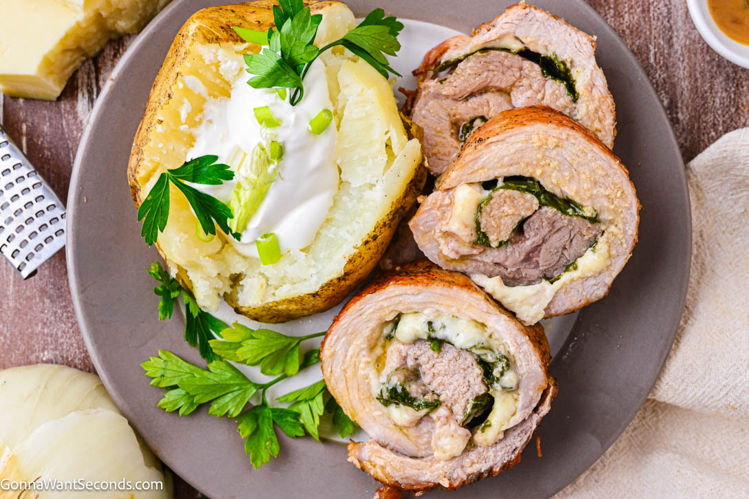 This stuffed pork tenderloin is juicy, tender, and filled with spinach + Gruyère, then finished with a silky white wine cream sauce. #stuffedpork #porktenderloin slices of stuffed pork tenderloin with spinach, gruyere with white wine cream sauce