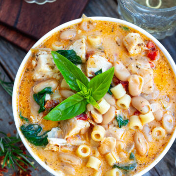 Creamy Tuscan chicken soup garnished with fresh basil on a bowl