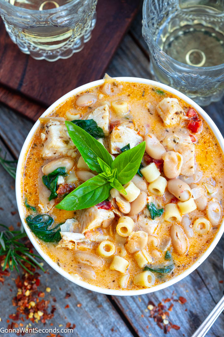 Creamy Tuscan chicken soup with juicy chicken breast, ditalini, sun-dried tomatoes, spinach, and Parmesan—cozy one-pot comfort for busy weeknights. #tuscanchickensoup #chickensoup Creamy Tuscan chicken soup garnished with fresh basil on a bowl