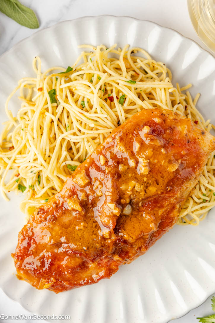 Chicken Saltimbocca is a fancy but easy, 30-minute pan-seared chicken cutlet, elegantly topped with sage and prosciutto, with white wine butter sauce. #chickensaltimbocca #30minutemeals a piece of Chicken Saltimbocca coated with sauce on top of pasta on a plate