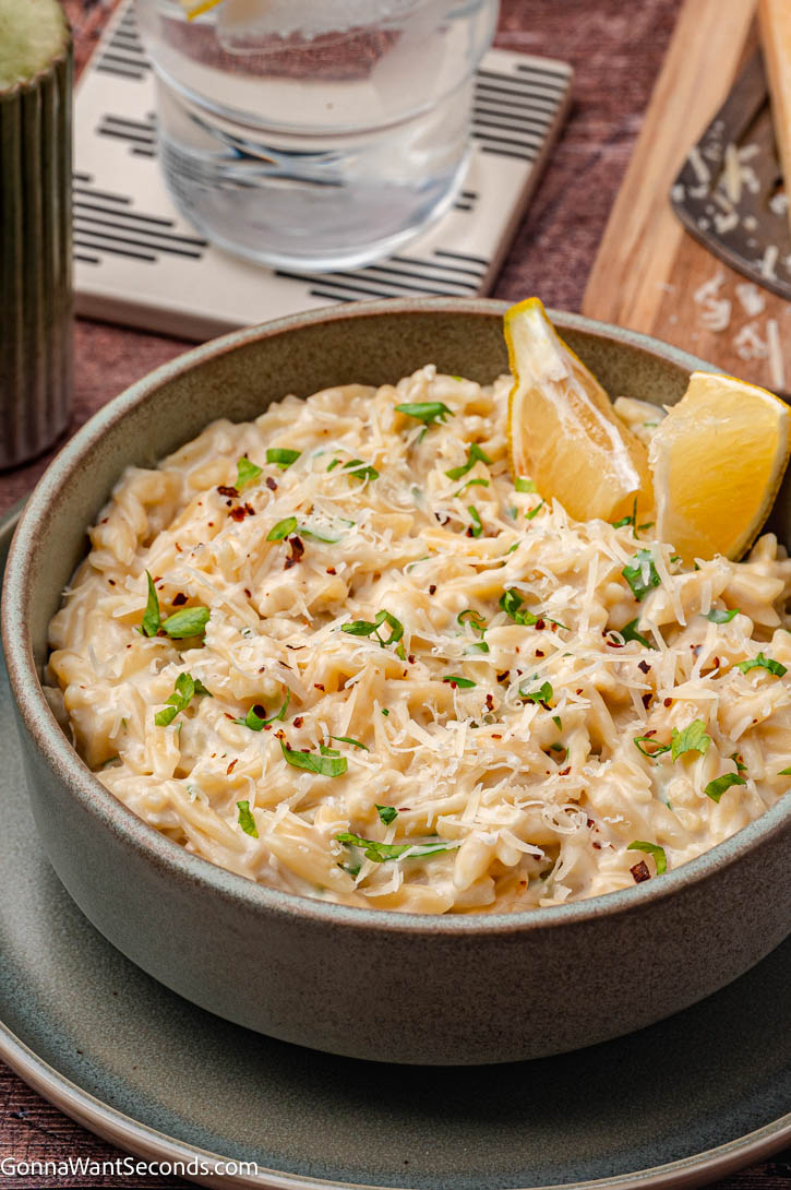 Creamy garlic Parmesan orzo made in one pan with simple ingredients. This easy side dish is rich, cozy, and perfect with chicken or beef dinners. #garlicparmesanorzo #creamygarlicparmesanorzo Creamy parmesan garlic orzo in a bowl with lemon wedges on top