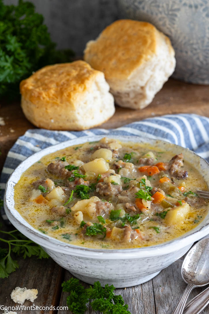 Hearty sausage potato soup with tender potatoes in a lightly creamy broth. One pot, stovetop, and ready in under an hour—perfect for busy nights. #sausagesoup #potatosoup A bowl of Sausage Potato Soup with biscuits on the side