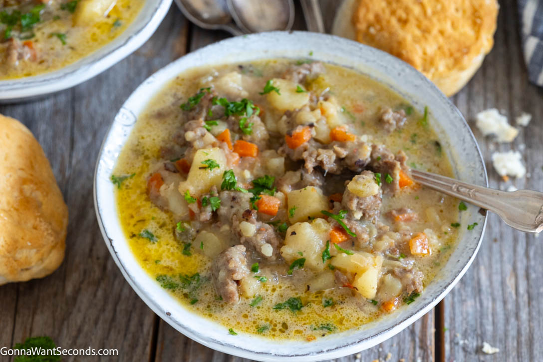 Hearty sausage potato soup with tender potatoes in a lightly creamy broth. One pot, stovetop, and ready in under an hour—perfect for busy nights. #sausagesoup #potatosoup a bowl of Potato and Sausage Soup with biscuits on the side