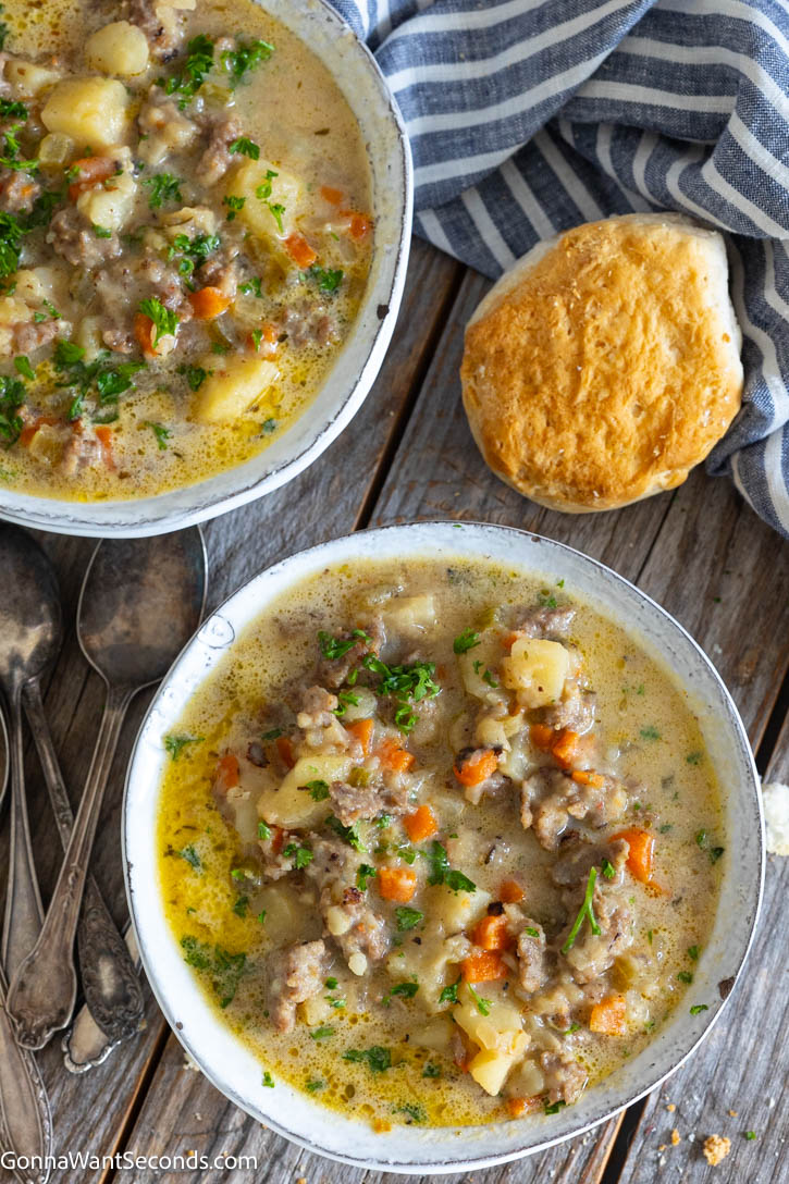 Hearty sausage potato soup with tender potatoes in a lightly creamy broth. One pot, stovetop, and ready in under an hour—perfect for busy nights. #sausagesoup #potatosoup bowls of Italian Sausage Potato Soup with biscuit on the side