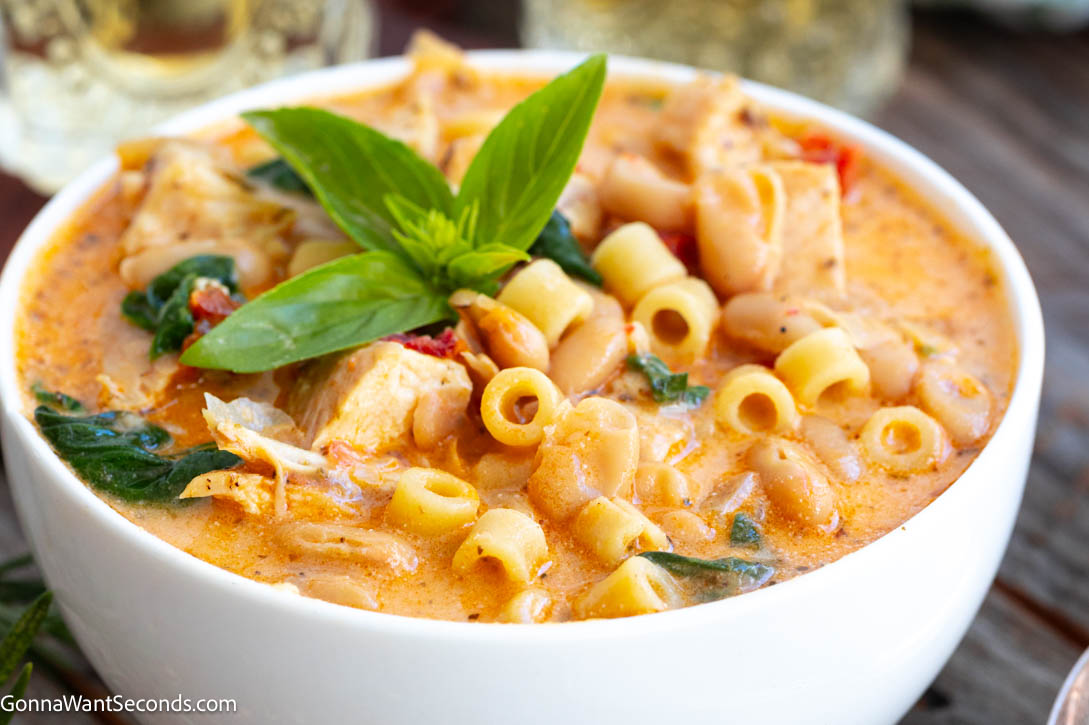 Creamy Tuscan chicken soup with juicy chicken breast, ditalini, sun-dried tomatoes, spinach, and Parmesan—cozy one-pot comfort for busy weeknights. #tuscanchickensoup #chickensoup Creamy Tuscan chicken pasta soup garnished with fresh basil on a bowl