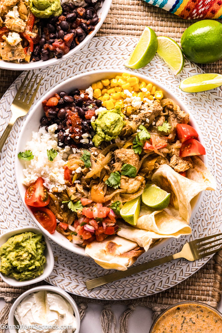Chicken Fajita Bowls loaded with lime-marinated chicken, sautéed peppers, rice, crisp greens, and creamy chipotle dressing. Easy, fresh, flavorful! #chickenfajitabowls #chickenfajita Chicken Fajita Bowls with lime wedges on the side