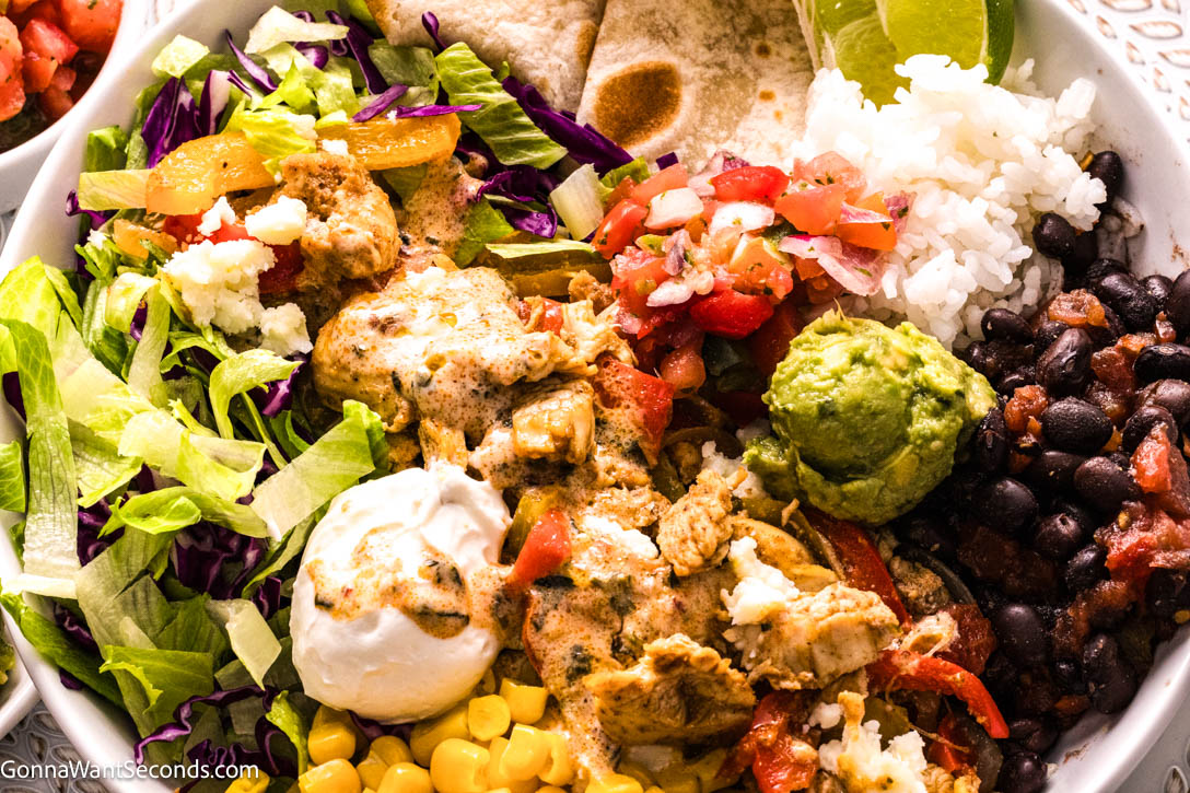 Chicken Fajita Bowls loaded with lime-marinated chicken, sautéed peppers, rice, crisp greens, and creamy chipotle dressing. Easy, fresh, flavorful! #chickenfajitabowls #chickenfajita chicken fajita bowls close up