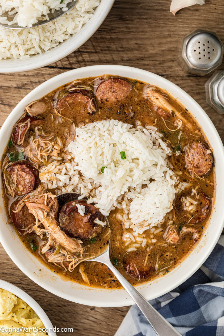 Authentic Cajun chicken and sausage gumbo with a deep dark roux, smoky andouille, and bold flavor. Tomato-free and rich. #chickengumbo #gumbo chicken and sausage gumbo with rice in a bowl