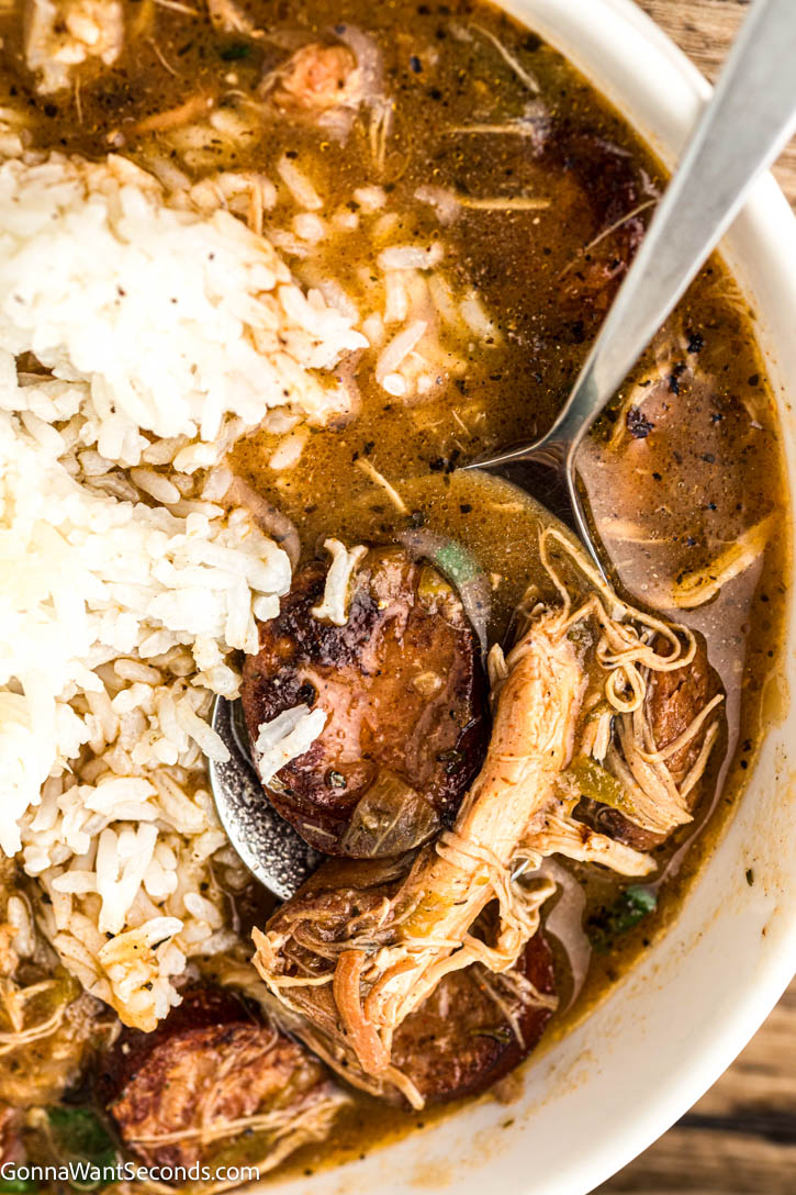 Authentic Cajun chicken and sausage gumbo with a deep dark roux, smoky andouille, and bold flavor. Tomato-free and rich. #chickengumbo #gumbo chicken and sausage gumbo with rice in a bowl