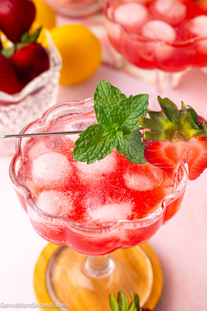 A bubbly, elegant strawberry mocktail perfect for brunches and warm evenings. Fresh strawberries, floral rosé flavor, and herbs shine in this alcohol-free sip. #strawberrymocktails #mocktails Strawberry mocktail garnished with mint leaces in a coupe glass
