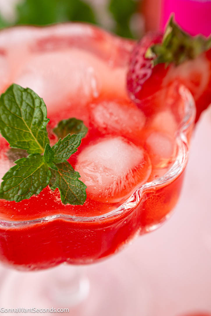 A bubbly, elegant strawberry mocktail perfect for brunches and warm evenings. Fresh strawberries, floral rosé flavor, and herbs shine in this alcohol-free sip. #strawberrymocktails #mocktails Strawberry mocktail garnished with mint leaces in a coupe glass