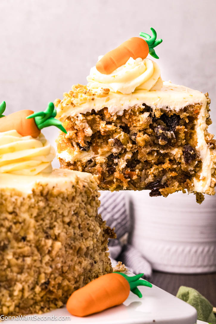 Ultra moist carrot cake with cream cheese frosting and a rich buttermilk glaze. Soft, bakery-style texture and perfectly spiced flavor. #carrotcake #creamcheesefrosting A slice of carrot cake lifted from the rest of the cake with a cake server