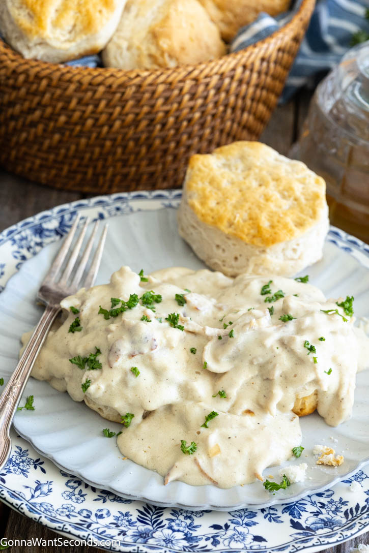 Creamed Chicken Over Biscuits is the ultimate comfort food. Enjoy tender chicken in savory gravy over warm biscuits with this easy, flavor-packed cozy recipe. #creamedchicken #chickenandbiscuits Creamed Chicken Over Biscuits on a plate with a biscuit on the side