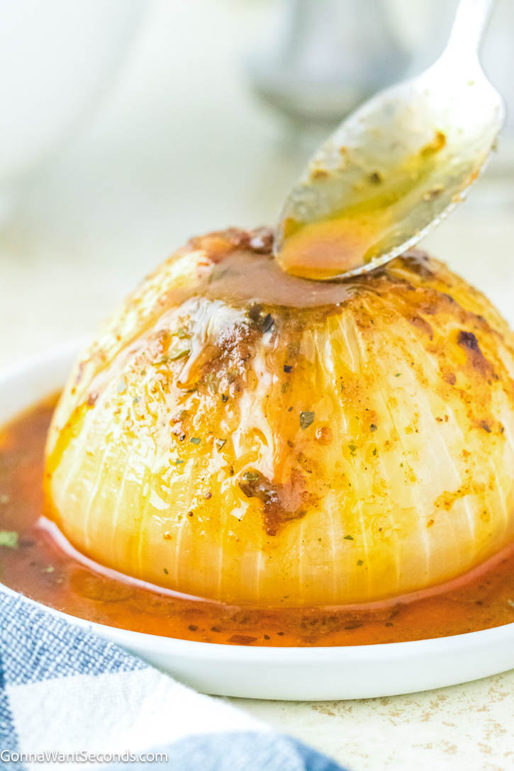 This viral onion boil recipe transforms onions into buttery, melt-in-your-mouth perfection. Easy, bold, and unbelievably good! #onionboil #sidedishes pouring cajun sauce over onion boil