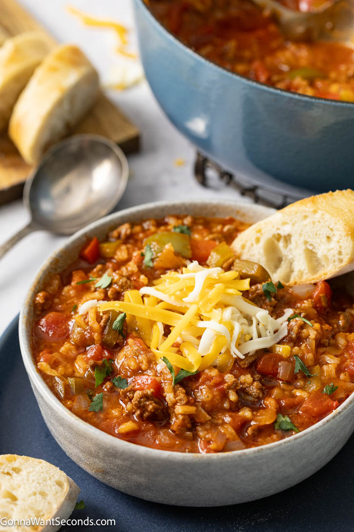 stuffed pepper soup topped with shredded cheese and a piece of bread