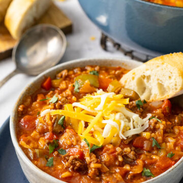 stuffed pepper soup topped with shredded cheese and a piece of bread