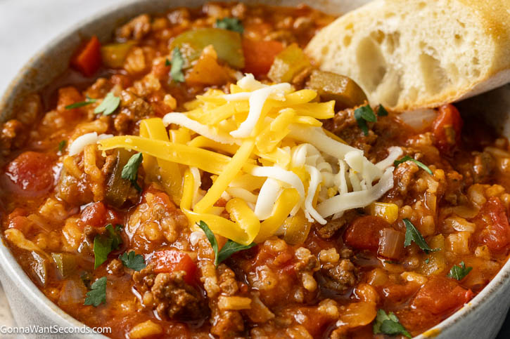 stuffed pepper soup topped with shredded cheese and a piece of bread