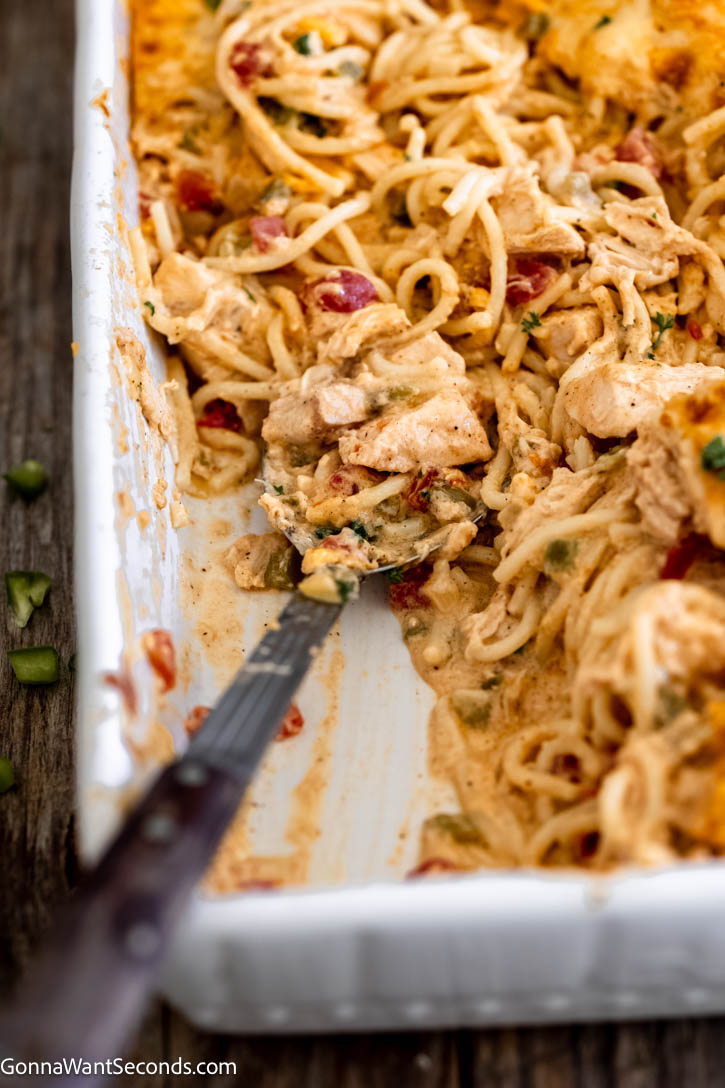 This best creamy chicken spaghetti is baked from scratch with a silky roux-based sauce, tender chicken, and melty cheese for the ultimate comfort food dinner. #creamychicken #chickenspaghetti serving fork scooping best creamy chicken spaghetti in a casserole