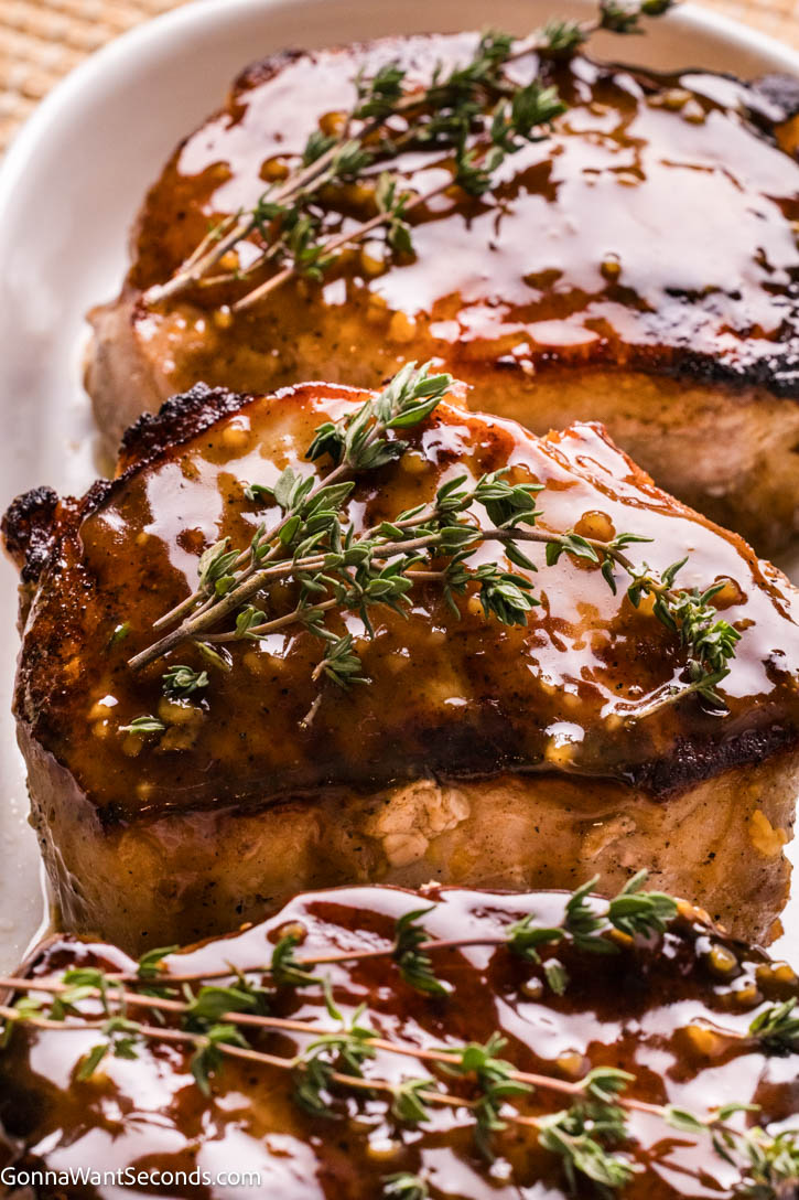 Golden, deeply seared on the outside and unbelievably juicy on the inside, these brown sugar pork chops are everything you want in a comfort dinner. #porkchops #brownsugarporkchops Brown Sugar Pork Chops with sauce on a serving platter