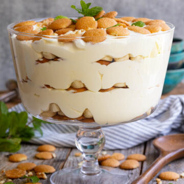 Magnolia Bakery banana pudding topped with vanilla wafers and mint leaves in a glass trifle bowl