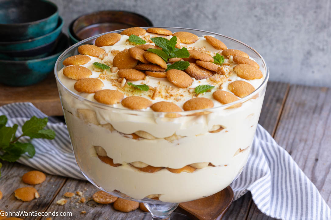 Magnolia Bakery banana pudding topped with vanilla wafers and mint leaves in a glass trifle bowl