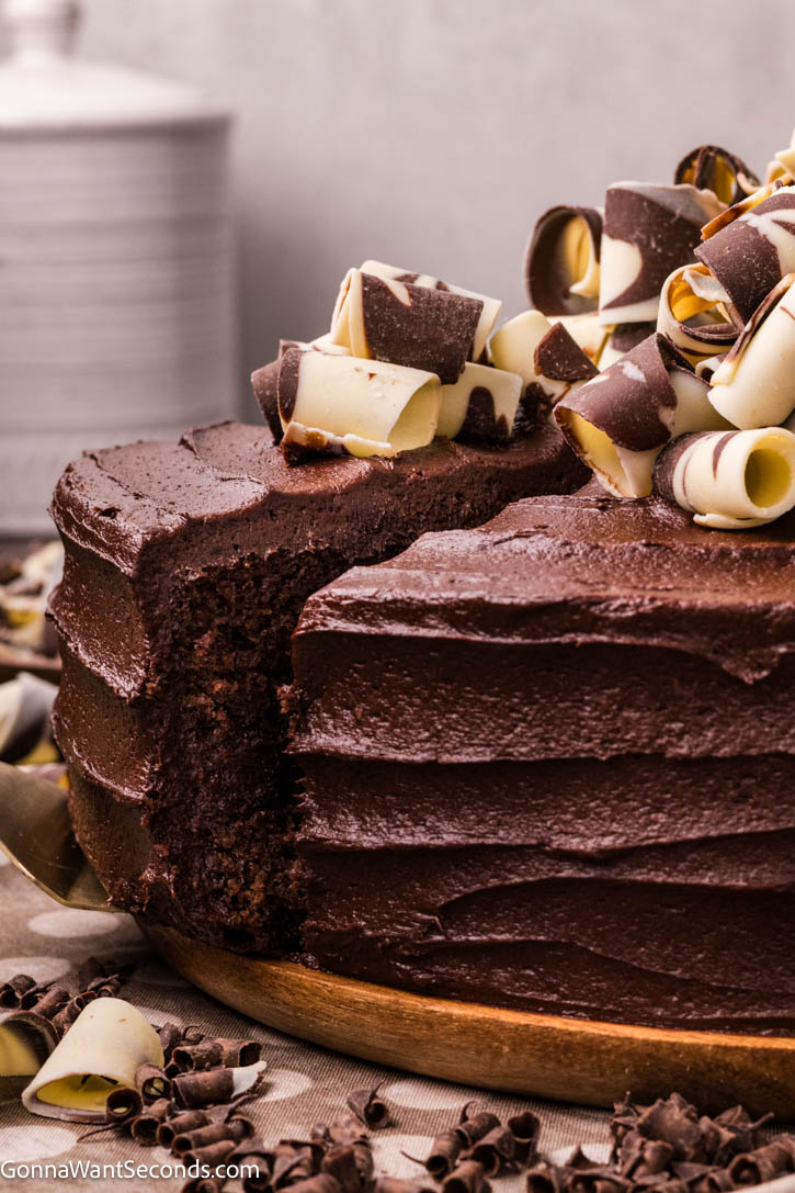 This Best Chocolate Cake is ultra moist, deeply chocolatey, and layered with silky fudge frosting. A rich homemade layer cake everyone will remember. #chocolatecake #bestchocolatecake a slice of best chocolate cake taking out from the whole cake