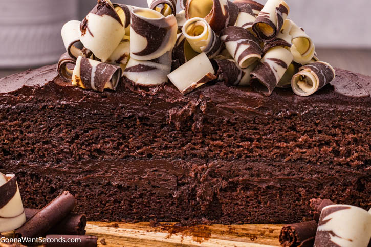 This Best Chocolate Cake is ultra moist, deeply chocolatey, and layered with silky fudge frosting. A rich homemade layer cake everyone will remember. #chocolatecake #bestchocolatecake best chocolate cake cut in half topped with chocolate swirls