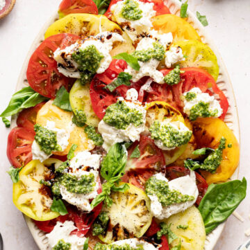Burrata Caprese Salad with dollops of pesto over the tomatoes and burrata with drizzles of balsamic glaze