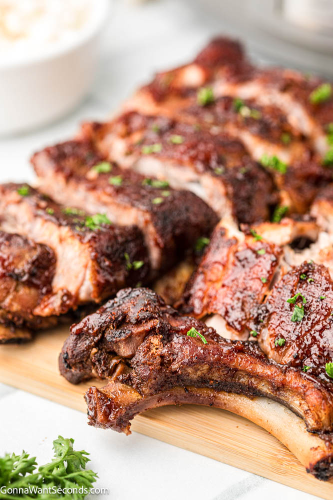 These Crockpot Ribs are tender, juicy, and coated in sticky caramelized BBQ sauce. An easy slow cooker rib recipe everyone loves. #babybackribs #crockpotribs sliced crockpot ribs on a wooden board