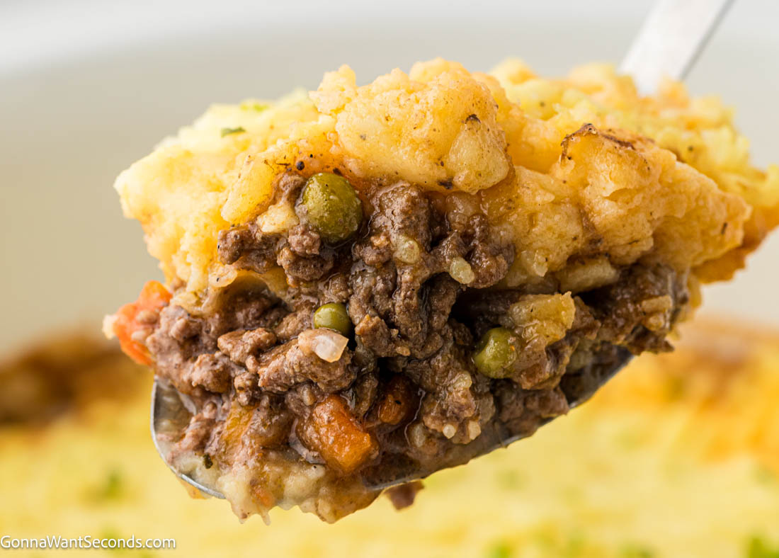 This Crockpot Shepherd's Pie has all the classic flavors: savory beef, rich gravy, tender vegetables, and creamy mashed potatoes, without the fuss of baking. #shepherdspie #crockpotrecipes serving spoon scooping Crockpot Shepherd's Pie